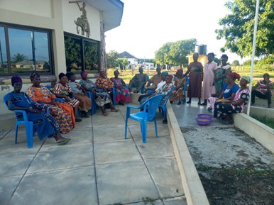 Women seated outdoors during a community meeting