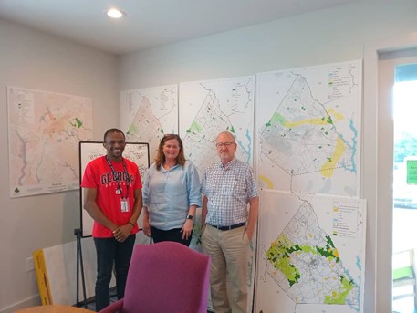 Three people standing in front of planning maps