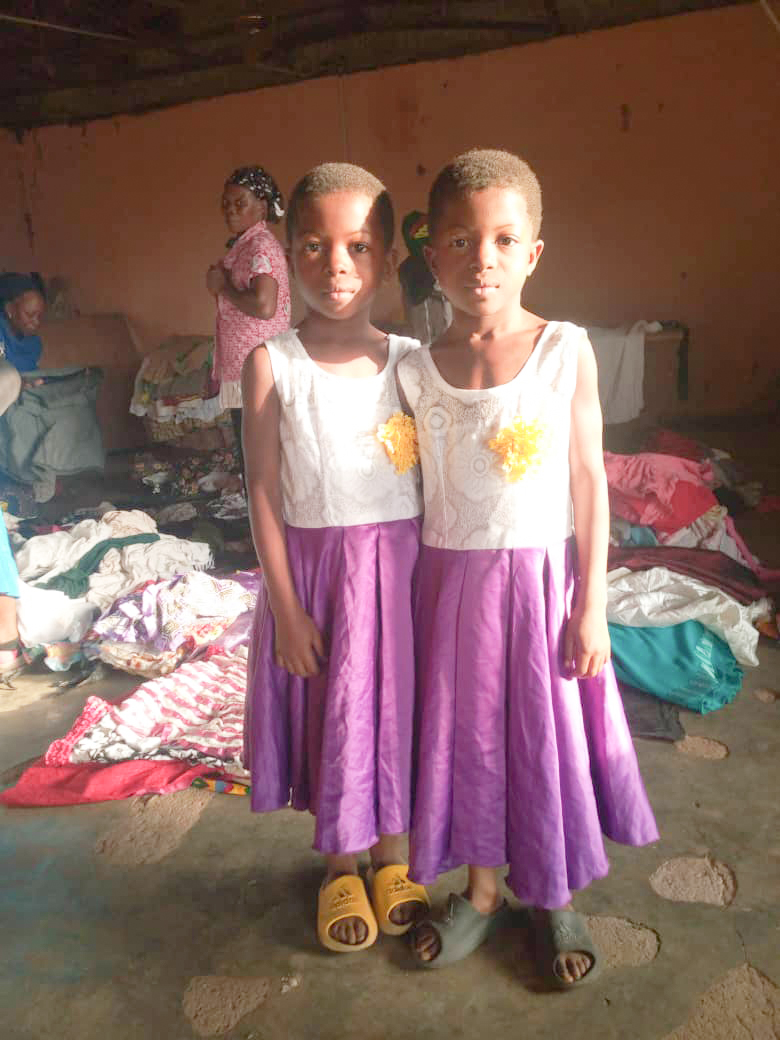 Two children standing in front of donated clothing