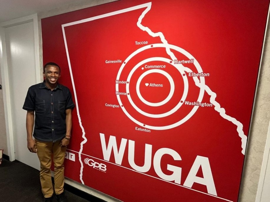 A man standing beside a large WUGA wall display