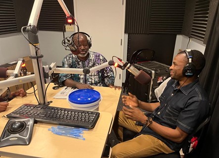 Two people seated at microphones in a radio studio